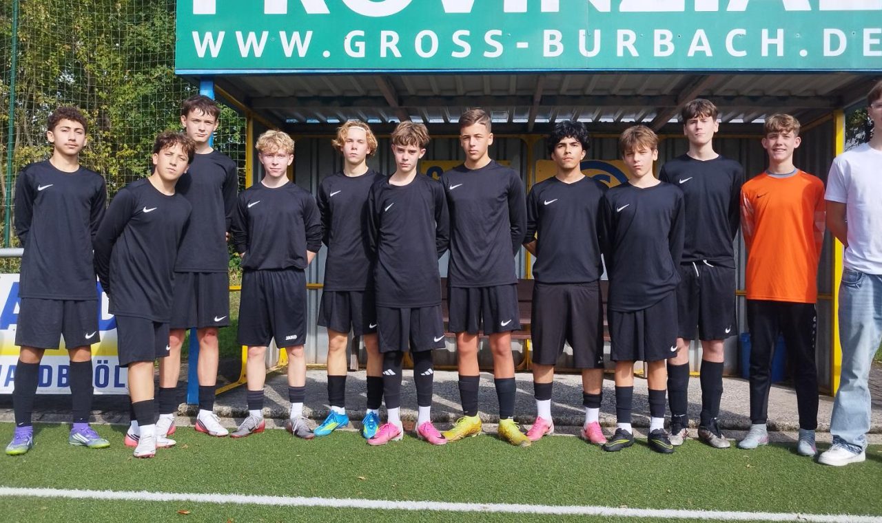 Eine Jugendfußballmannschaft steht auf einem Platz in schwarz-weißen Trikots.