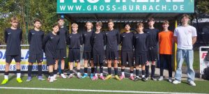 Eine Jugendfußballmannschaft steht auf einem Platz in schwarz-weißen Trikots.
