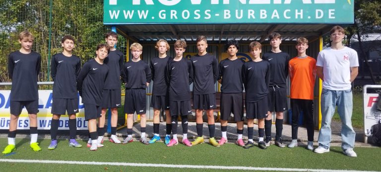 Eine Jugendfußballmannschaft steht auf einem Platz in schwarz-weißen Trikots.